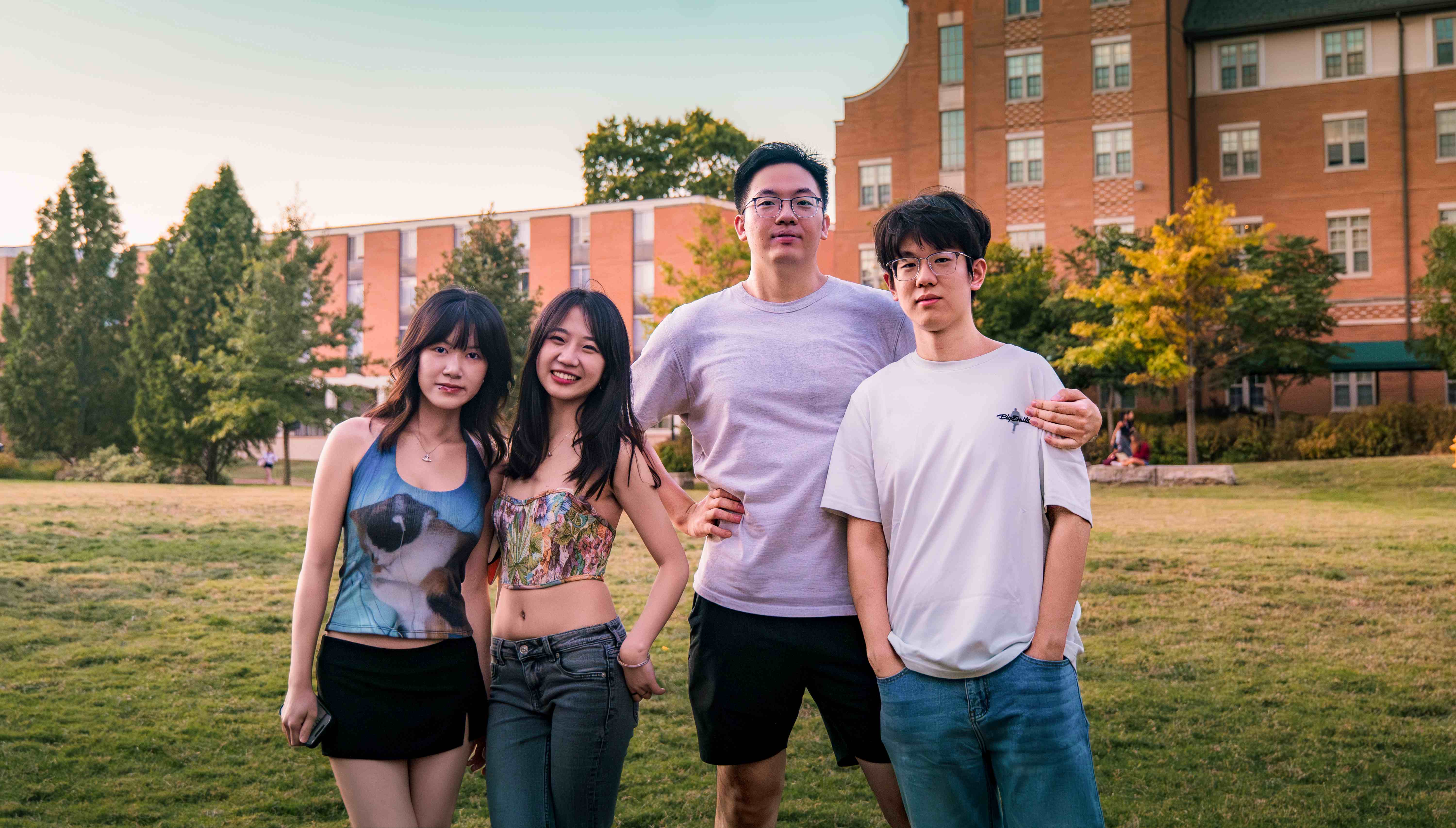 乐队成员四人在草地上合影,背景是红砖建筑