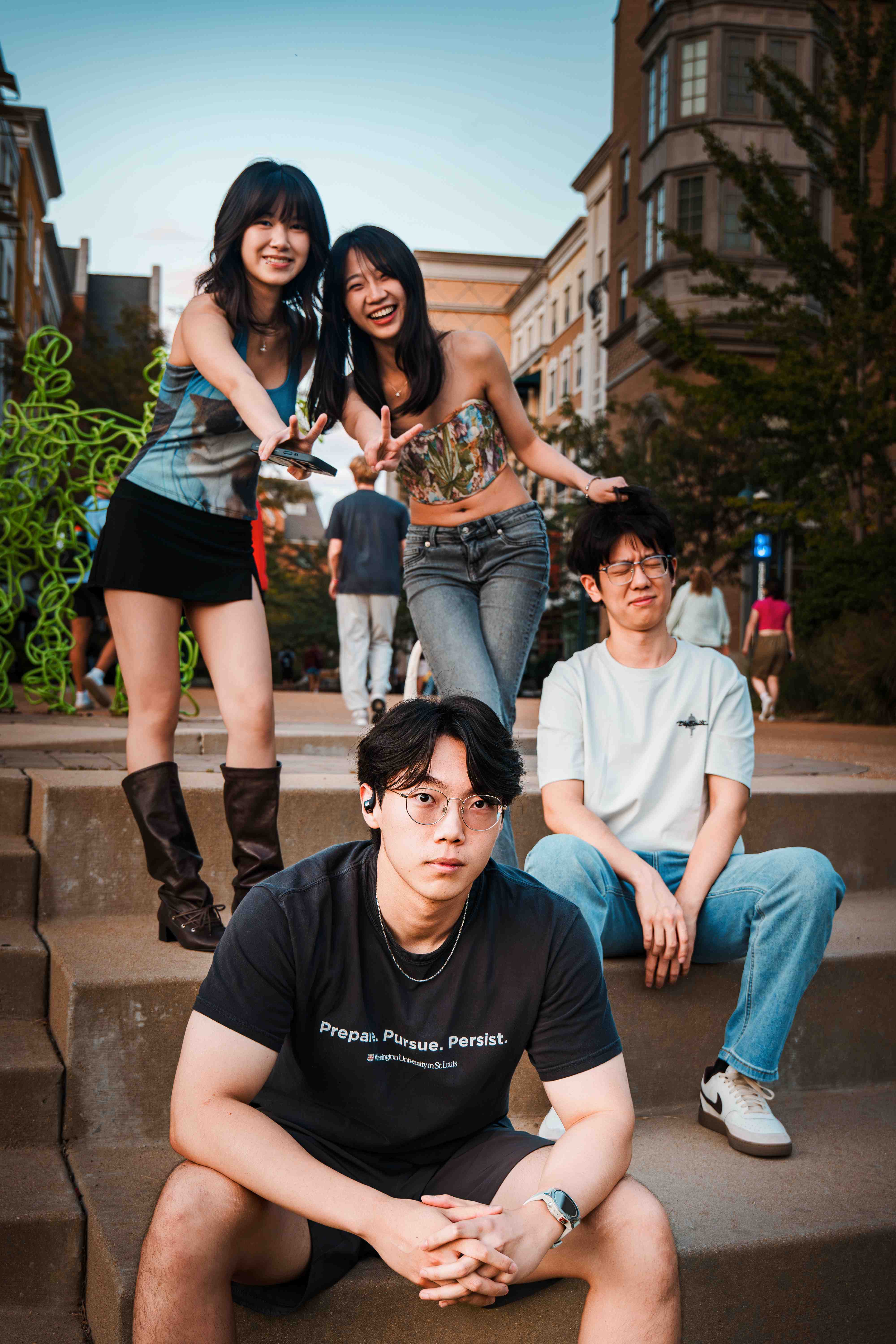 四位乐队成员在台阶上合影,两个女生站着做V手势